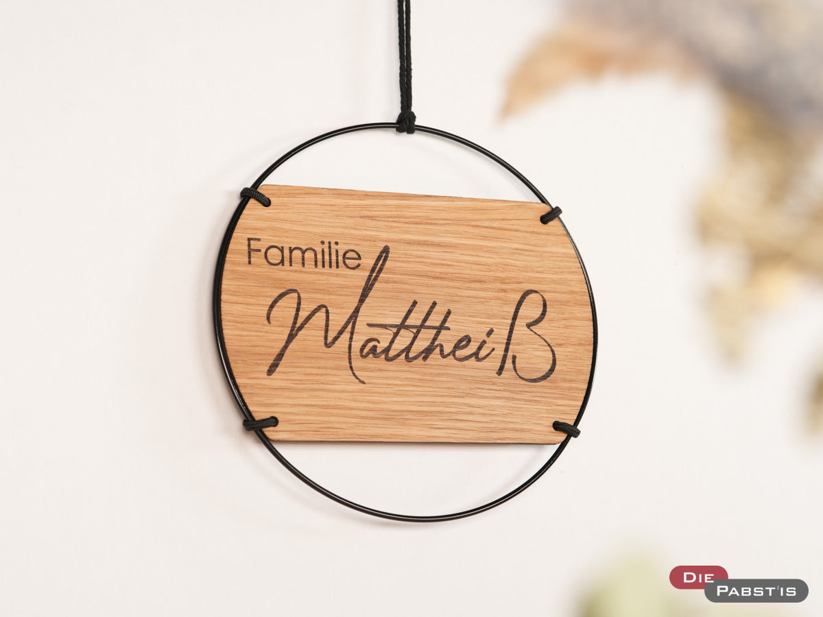 Modernes Holzschild mit schwarzem Metallring und Gravur Familie und deinem Nachname – personalisierte Deko für Haustür oder Flur.