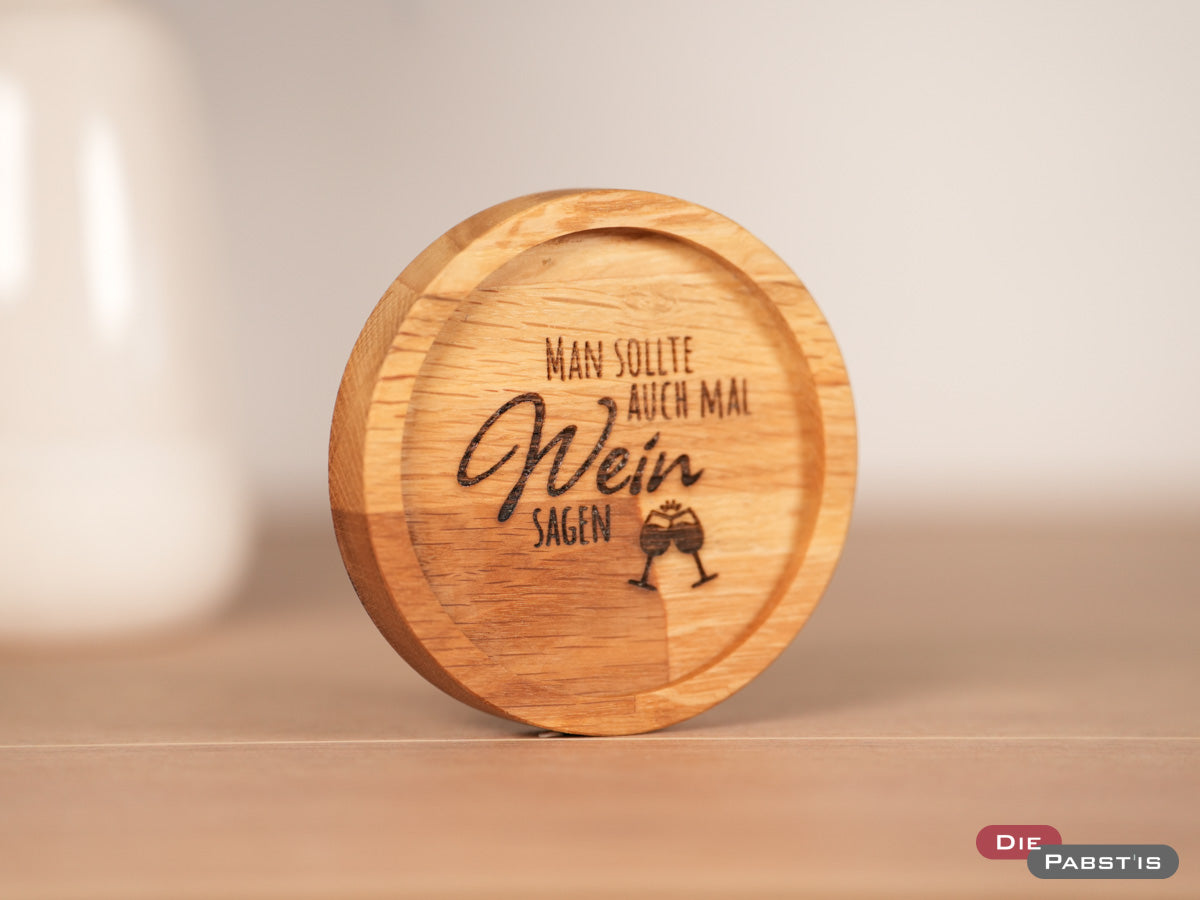 Untersetzer aus Eichenholz mit Gravur ‚Man sollte auch mal Wein sagen‘ – perfekt für gemütliche Abende mit einem Glas Wein.