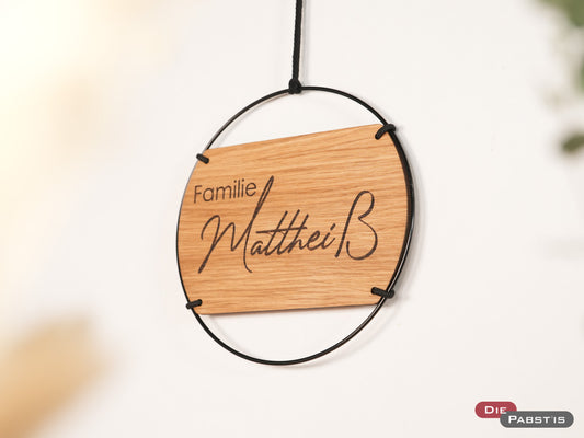 Personalisiertes Türschild aus Holz in Eichenoptik mit schwarzem Metallring und Gravur: Familie inkl. Nachname - stilvoller Willkommensgruß für dein Zuhause.